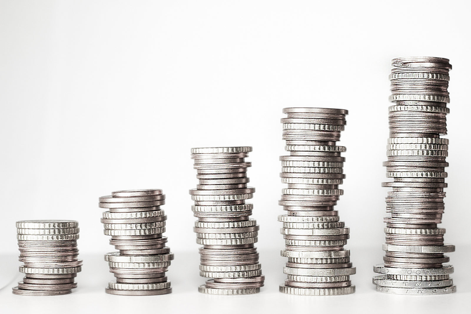 Five stacks of coins arranged in ascending height against a white background, representing growth and increasing value.